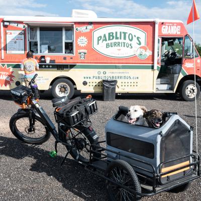 Bicycle with dogs in a trailer, in front of a food truck.