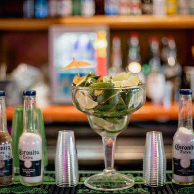 Margarita glass filled with limes next to shot glasses and salt shakers