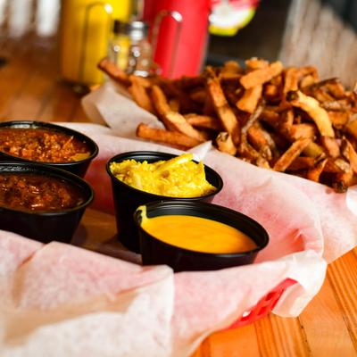 Chili, slaw, cheese dip, and fries on a dining table.