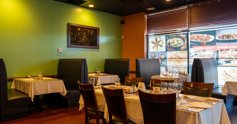 Cozy restaurant interior with green walls, elegant tables set with white tablecloths and glassware