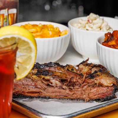 Brisket plate featuring sides on mac and cheese, yams, potato salad and a dip.