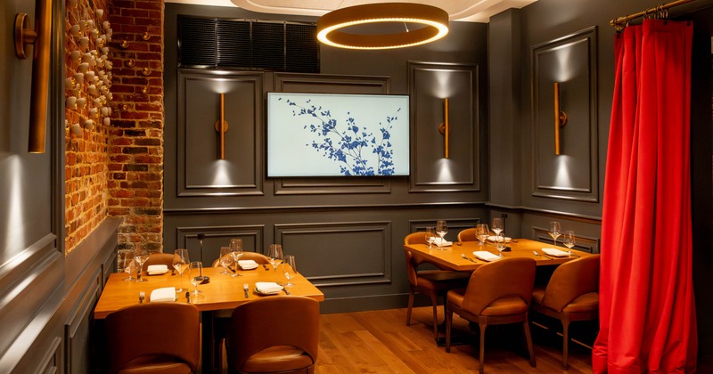 A stylish dining room with wood tables, leather chairs, and decorative lighting