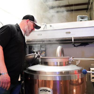 An employee inspects a brew kettle in a brewery.