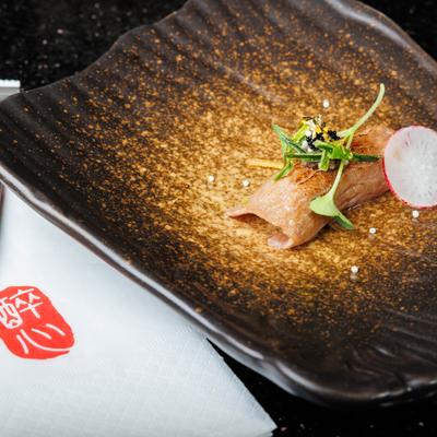 Toro fatty tuna sashimi garnished with microgreens and slice of radish.