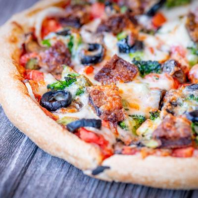 Veggie Pizza on a wooden table, close up.