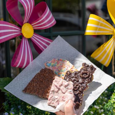 Various flavors of chocolate bark held in front of colorful pinwheels outside.