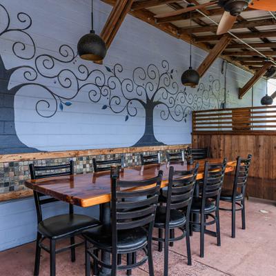 Covered patio area with painted tree mural on the wall and table seating.