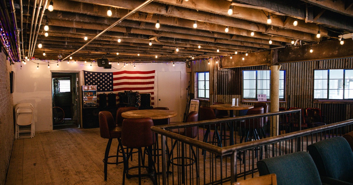 Cozy venue with exposed beams, warm lighting, round wooden tables