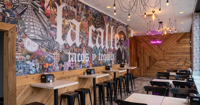 Interior of a restaurant with colorful wall art and a pink neon sign