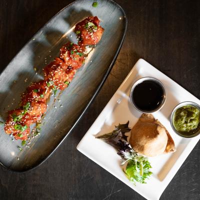 Top view of fried cauliflower florets with a soy-tomato glaze and a samosa.