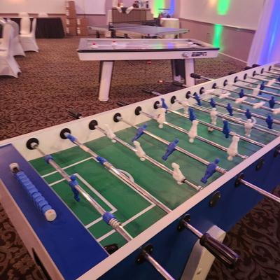 Foosball table with other game tables in a decorated event room.
