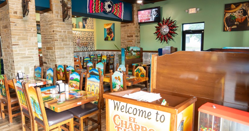 Interior of a colorful Mexican restaurant with painted chairs and rustic decor