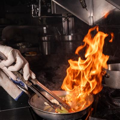 Chef tossing food in a pan with flames.
