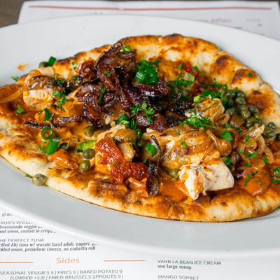 Chicken flatbread topped with caramelized onions, capers, and sun-dried tomatoes.