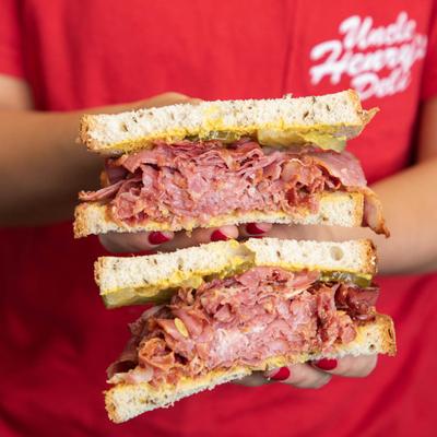 Attendant's hands holding Uncle Harrys Mix sandwich on display