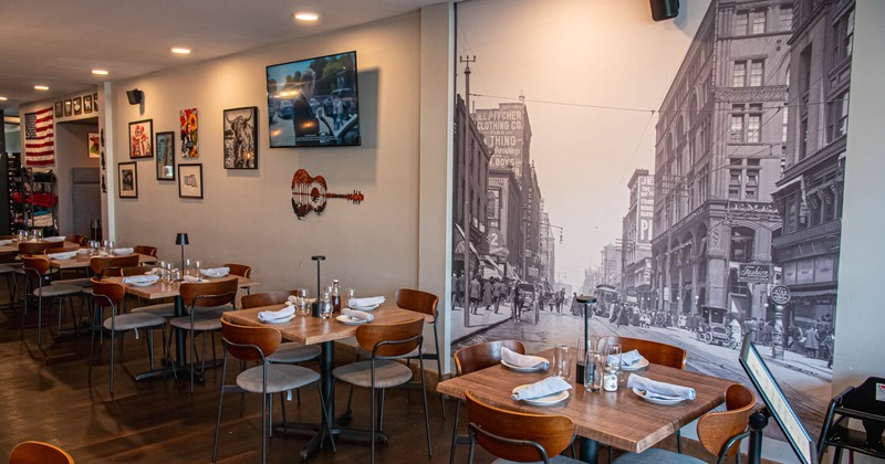 Restaurant interior with wooden tables, modern chairs, and a large mural