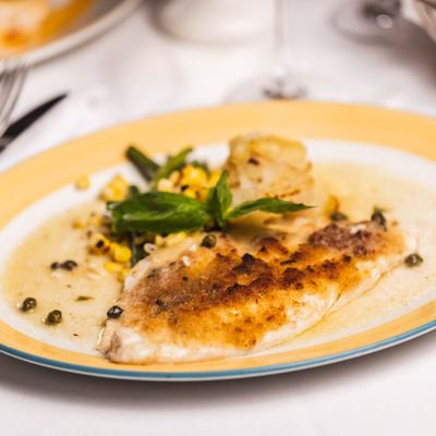 Baked branzino fillet, with white wine sauce, capers, and veggies.