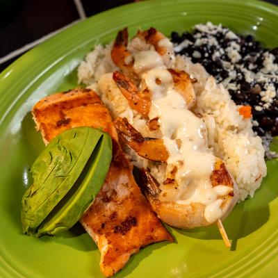 Grilled shrimp and salmon with rice, beans, and avocado.