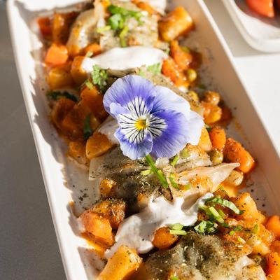 Steamed dumplings ﬁlled with ground lamb, onions, topped with yogurt, and vegetables.