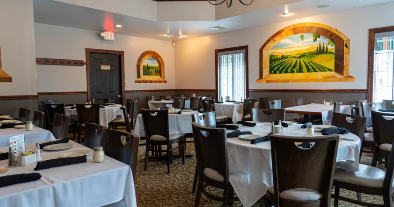 Interior, white tablecloths, black napkins, vineyard murals and central chandelier