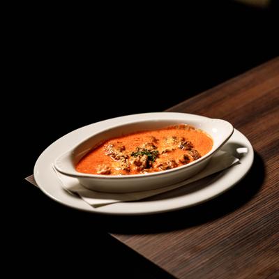 Escargot Alla Medici served in a casserole dish and garnished with fresh herbs.
