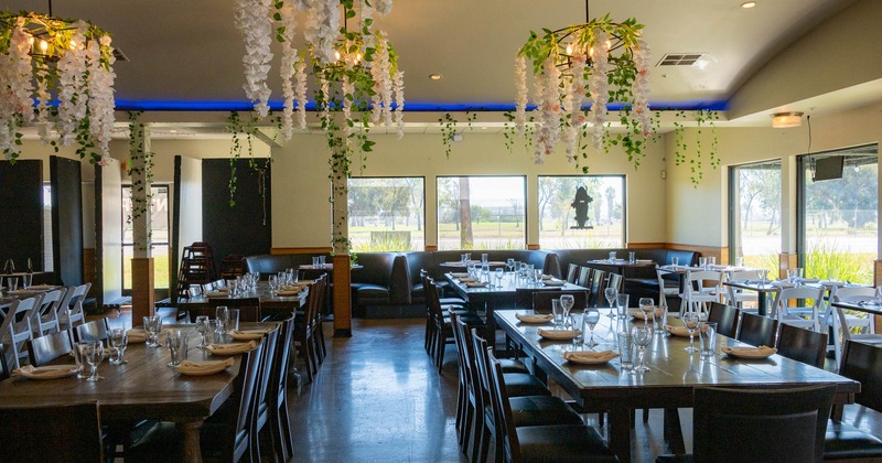 Interior with tables set for dining, featuring hanging floral decorations and large windows