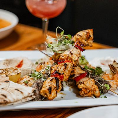 Grilled chicken and beef skewers on a plate with pita bread and sides