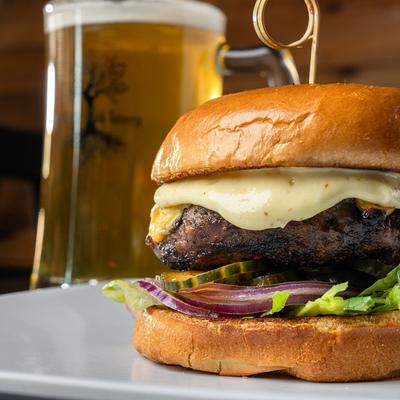 Cheeseburger with lettuce onion pickles and beer.