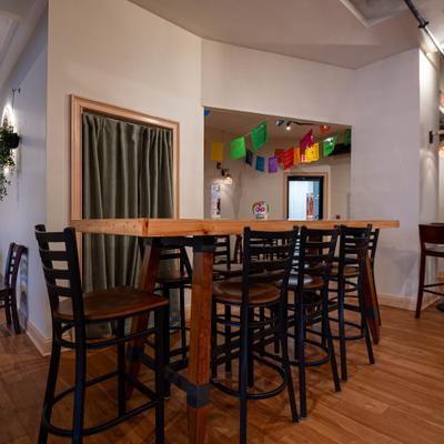 Interior with high-top wooden table with several dark wooden bar stools.