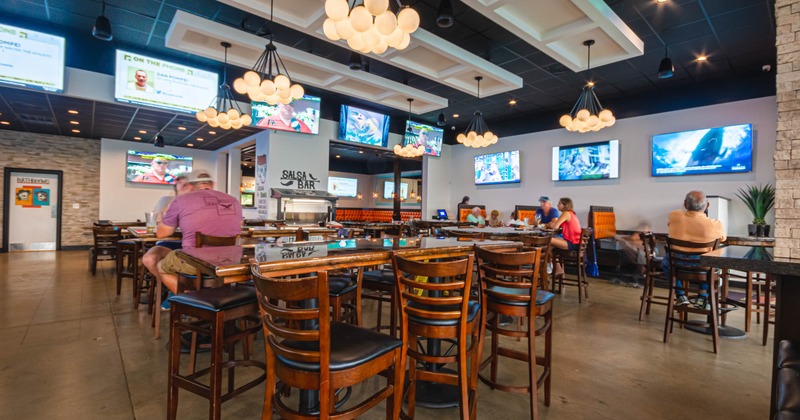 Interior, guests in the seating area, large TV screens on walls around the room