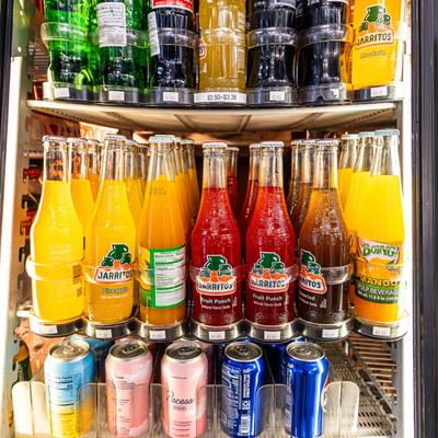 Colorful beverages on refrigerator shelves.