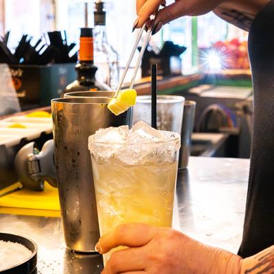 Bartender garnishig a cocktail using tweezers.