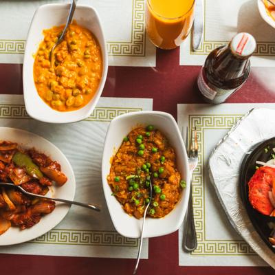 Assorted curry dishes and drinks on a patterned table.