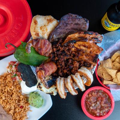 Molcajete surrounded by food plates and a beer, top view.