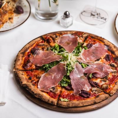 Prosciutto pizza with fresh greens.