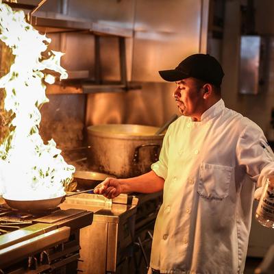 Chef cooking with a large flame coming out of the pan.