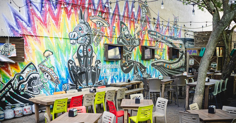 Long table, small tables, colorful chairs, big mural on the wall