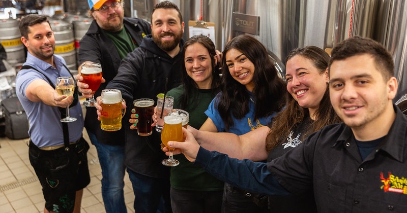 Inside brewery, staff making a toast with beers for the camera