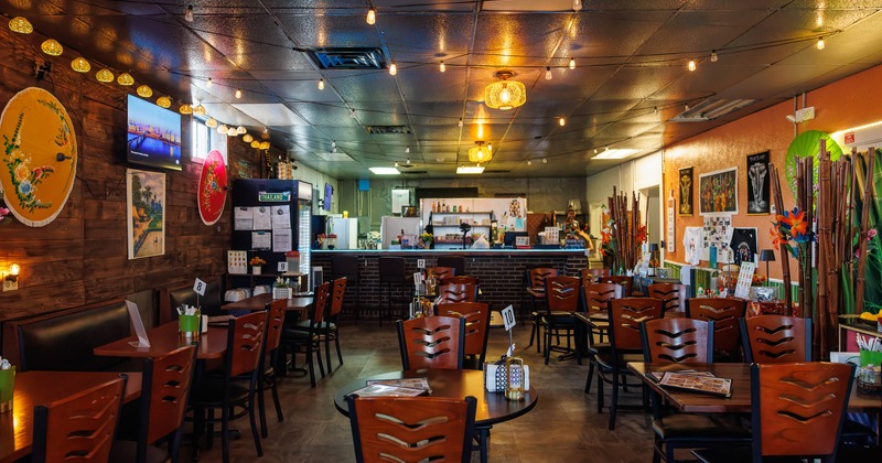 Restaurant interior with wooden tables, colorful umbrellas, and warm lighting