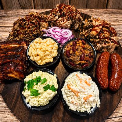 Wooden board with BBQ meats and side dishes.