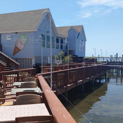 Outdoor dining area on a wooden dock with tables and chairs.