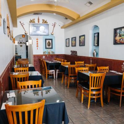 Thai restaurant featuring wooden chairs, black tablecloths, and traditional wall decor.