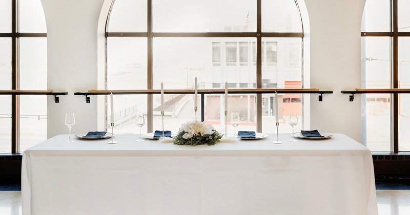 Interior, an elegantly arranged table covered with white tablecloth, with tableware