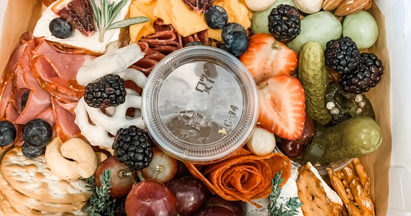 Charcuterie with cheese, crackers , berries, grapes, nuts, and pickles, top view