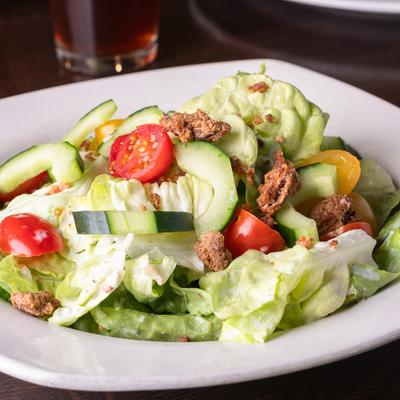 Salad with candied pecans, cherry tomatoes, cucumbers, and bacon.