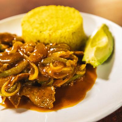 Steak with onions and hot peppers, served with rice and avocado.