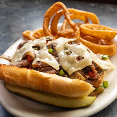 Philly cheesesteak served with onion rings.
