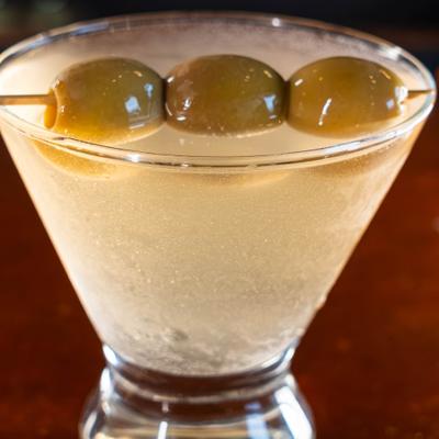 Dirty martini cocktail in a stemless glass with olive garnish
