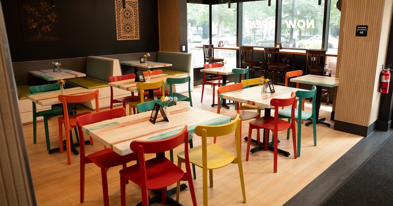 Interior of a cozy and vivid dining area with wooden tables and colorful chairs