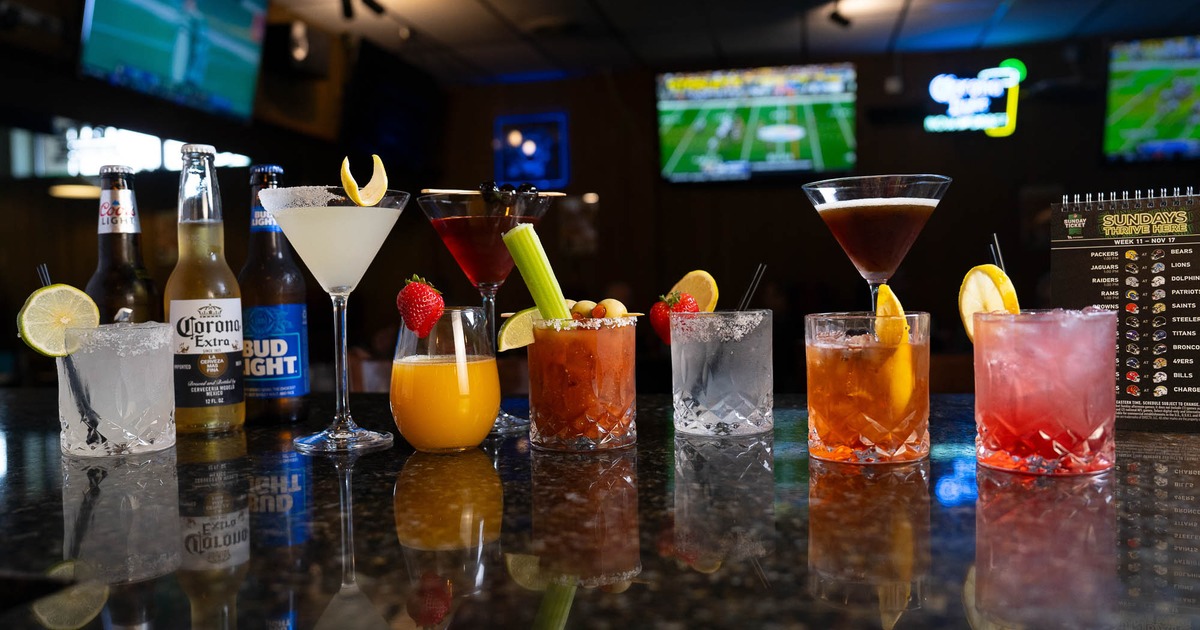 Assorted cocktails lined on dark bar counter